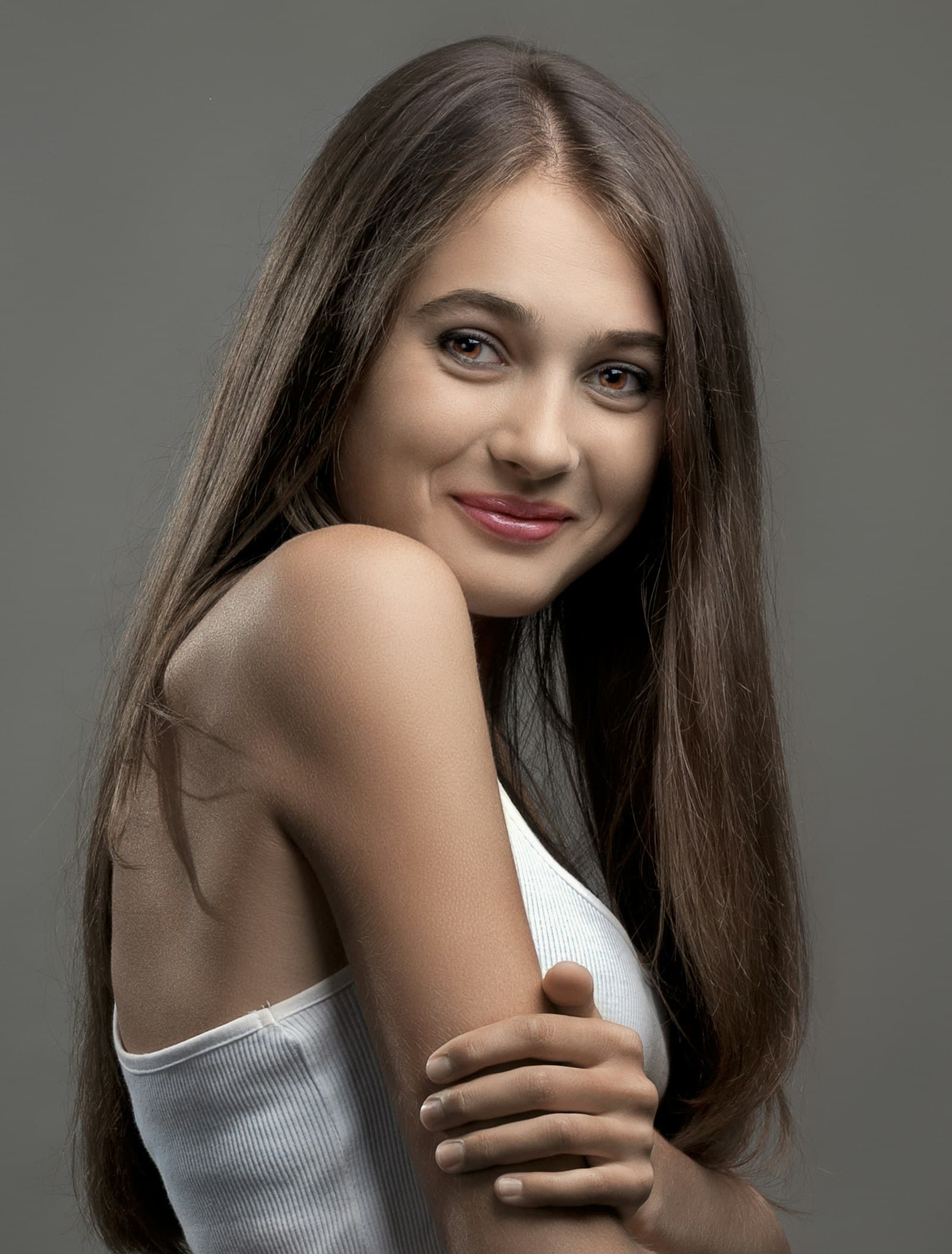A smiling woman with long dark hair, looking over her shoulder